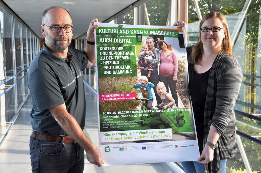 Michael Werner und Carolin Röttger halten ein Plakat in den Händen zum Thema Online-Vorträge zum Klimaschutz.