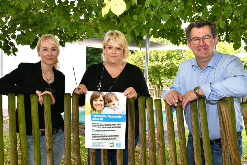 Stephanie Werk-Ferber, Christina Westermeier und Christian Rodemeyer werben für Tagesmütter/Tagesväter mit einem Plakat.