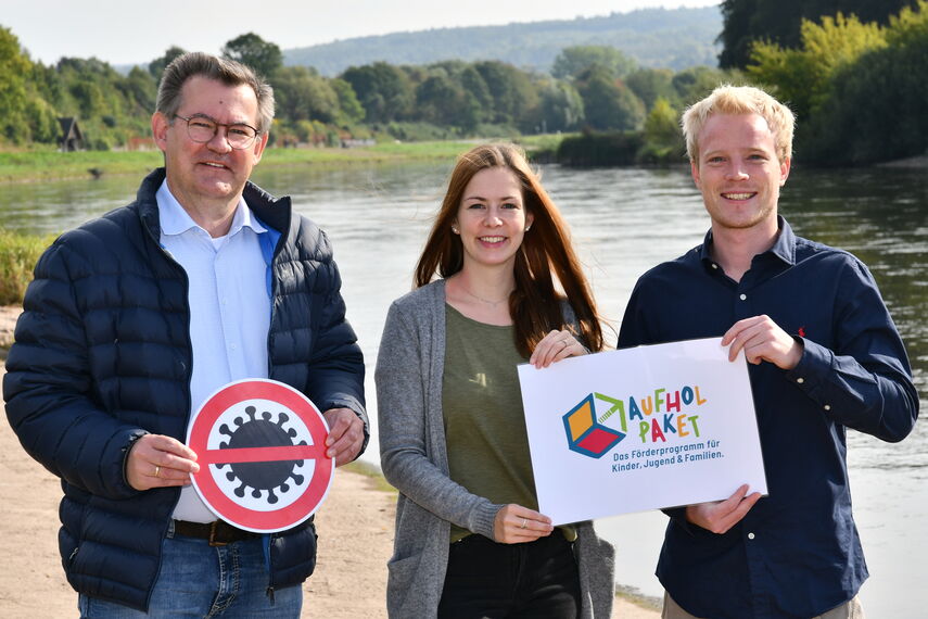 Christian Rodemeyer, Deborah Frischemeier und Rouven Speith stehen an der Weser in Höxter und stellen das 'Aufholpaket' vor.